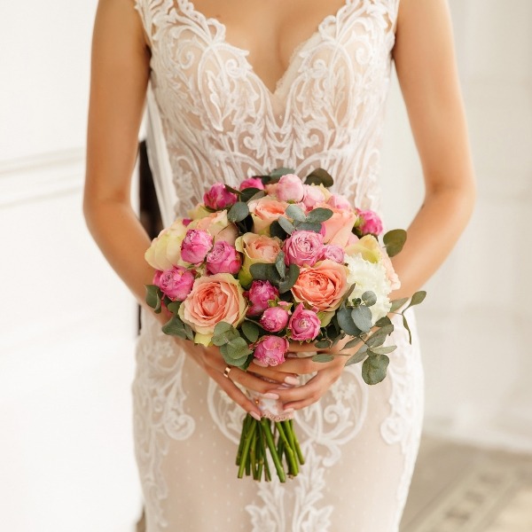 detail shot of lacey wedding dress and rose bouquet