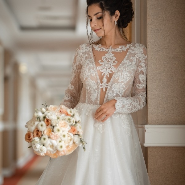 bride with low cut lacey wedding gown and orange and white flowers